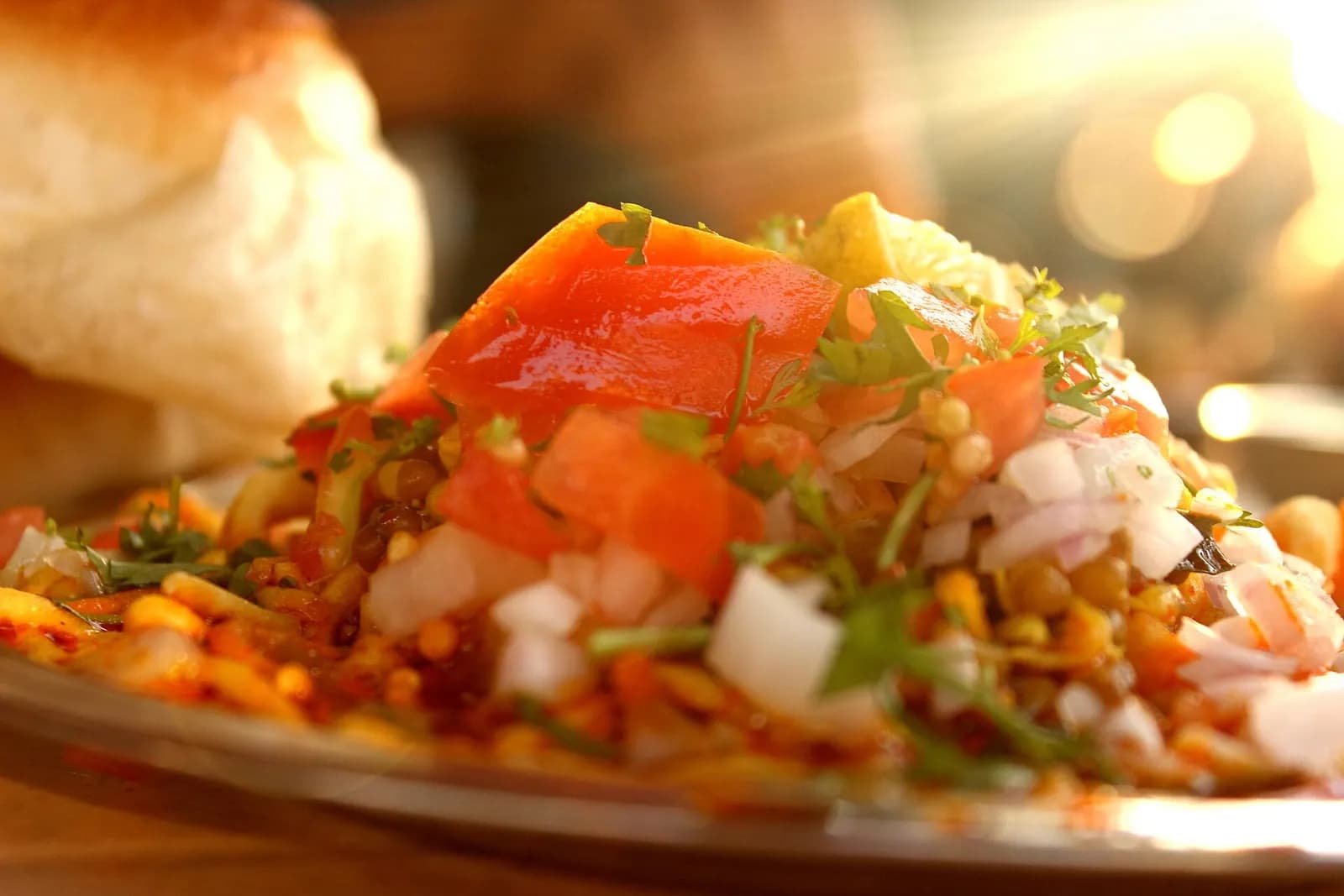A plate of misal with onion, tomato and farsan